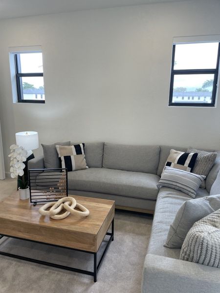 A cozy living room with gray sofas, a chic wooden coffee table, decorative pillows, and modern accents.