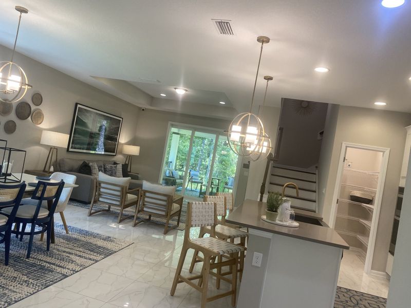 A modern open-concept living area with elegant lighting, cozy seating, and a view of the greenery through large sliding doors. A modern open-concept living area with elegant lighting, cozy seating, and a view of the greenery through large sliding doors.