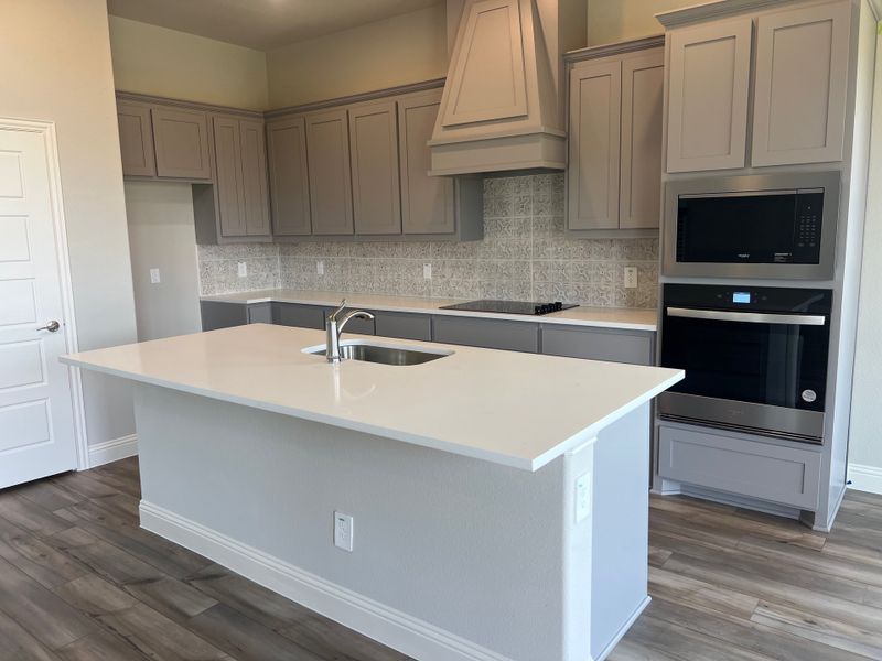 A modern kitchen with sleek gray cabinetry, a spacious island, and wood flooring for a contemporary feel.