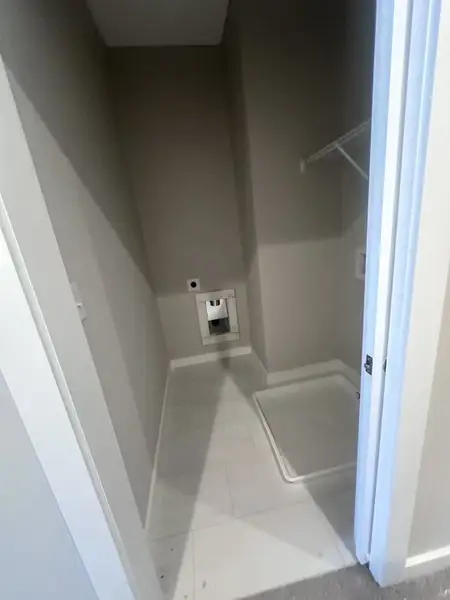A compact laundry room with tiled flooring and space for a washer and dryer hookup.