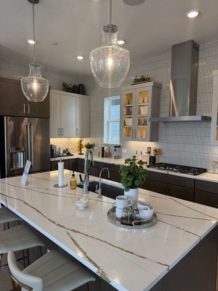 A modern kitchen featuring a marble island, sleek cabinetry, stainless steel appliances, and elegant pendant lighting.