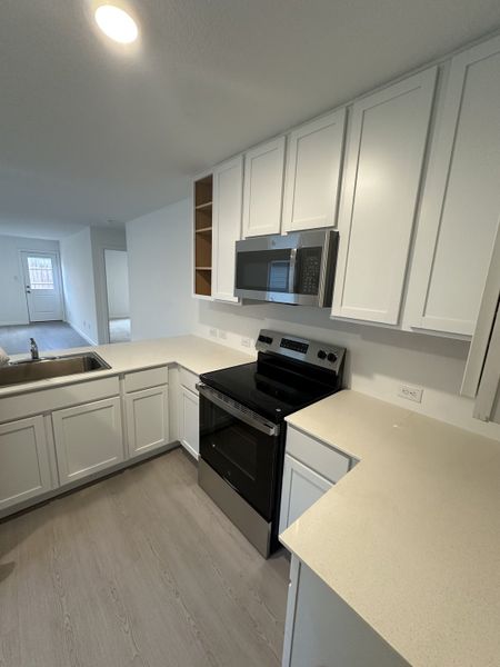 Modern kitchen with sleek white cabinets, stainless steel appliances, and ample counter space for easy cooking.