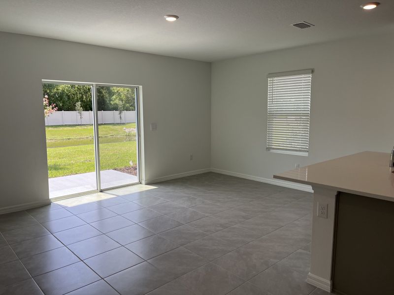 Bright living space with large tiles, sliding doors to a lush backyard, and ample natural light.