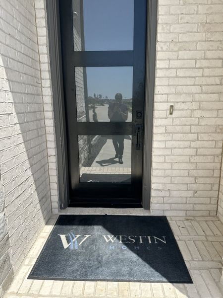 A sleek entrance with a glass door, accented by a Westin Homes mat at The Trails - 60' in New Caney, TX.