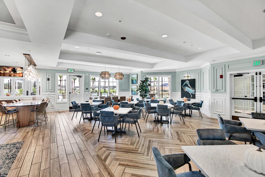Community clubhouse dining room with herringbone wood floors, blue chairs, and large windows
