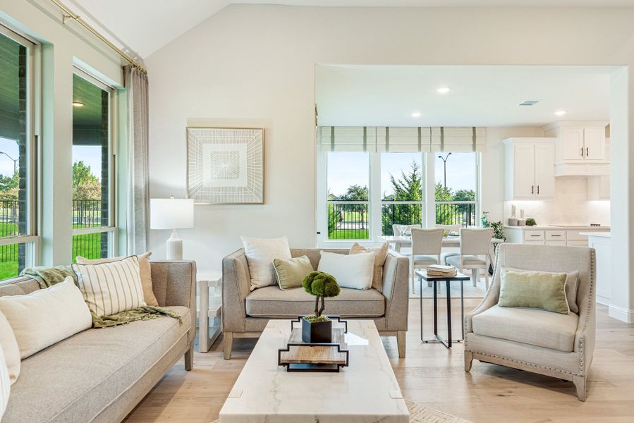Open-concept living room with neutral furniture, hardwood floors, and large windows overlooking a backyard Open-concept living room with neutral furniture, hardwood floors, and large windows overlooking a backyard