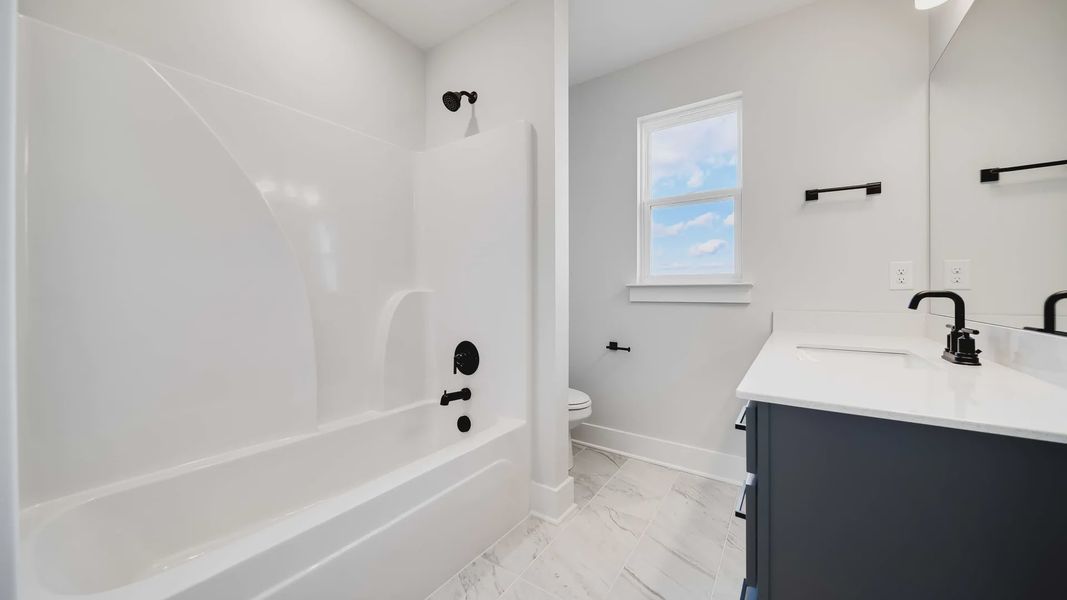 Luxurious bathroom featuring sleek black fixtures, elegant marble tile, and bright ambiance. Richvale Estates.
