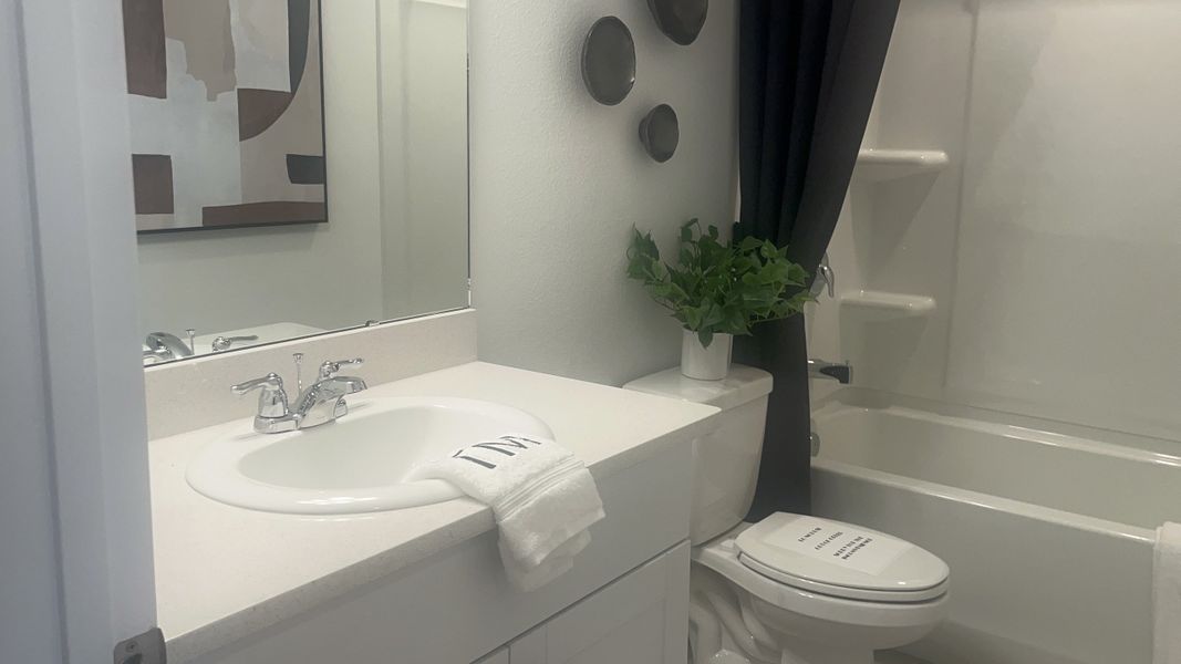 A modern bathroom with elegant fixtures, sleek white countertop, and artistic wall decor.