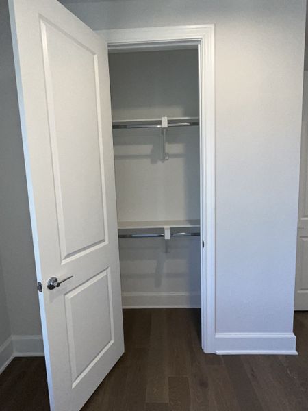 A spacious walk-in closet with sleek wooden floors and modern white doors, perfect for ample storage solutions. A spacious walk-in closet with sleek wooden floors and modern white doors, perfect for ample storage solutions.