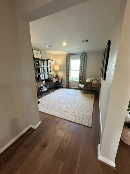 A cozy office nook with a plush armchair, elegant bookshelf, and abundant natural light.