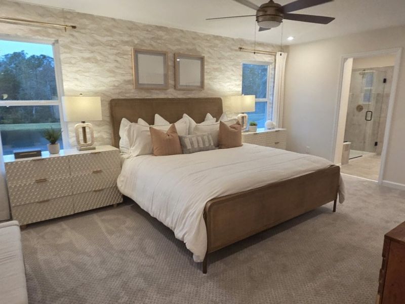 A cozy bedroom with a plush bed, stylish wallpaper, dual nightstands, and a modern en-suite bathroom.