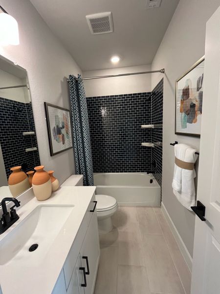 A contemporary bathroom features a sleek black-tiled shower, elegant vanity, and stylish decor for a modern touch.