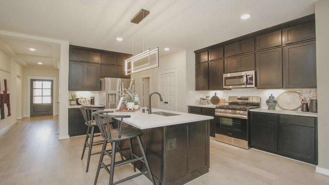 Elegant dark cabinetry and sleek pendant lighting enhance the sophisticated kitchen in Colony at Pinehurst.