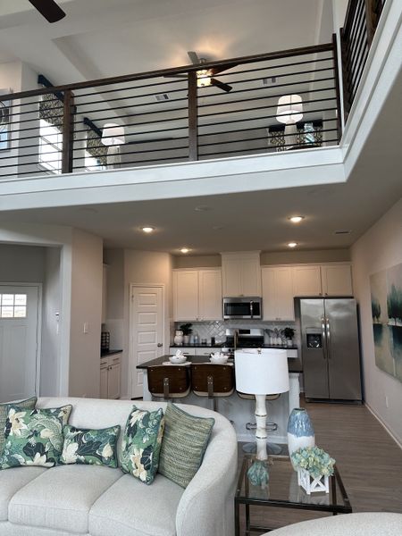 An airy living room with a loft view, modern kitchen, and stylish decor.