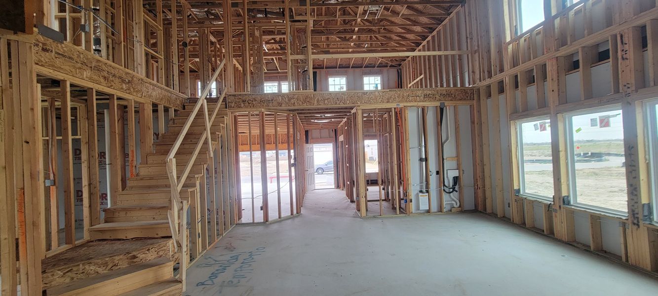 A spacious home under construction with exposed wooden framing and large windows.