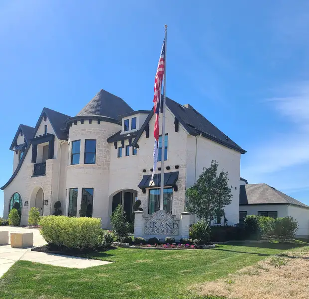 Elegant stone home with turrets and manicured landscaping in Silverleaf Estates in Frisco by Grand Homes (Frisco, TX).