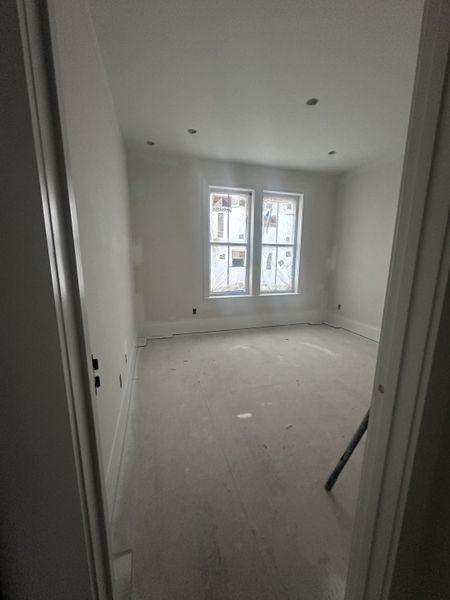 A bright, unfinished room with recessed lighting and large windows, ready for customization.