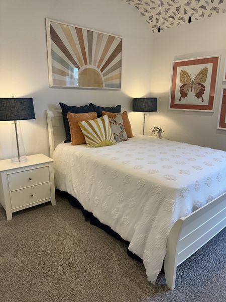 A cozy bedroom with butterfly wallpaper, abstract art, and plush bedding, creating a welcoming and artistic atmosphere. A cozy bedroom with butterfly wallpaper, abstract art, and plush bedding, creating a welcoming and artistic atmosphere.