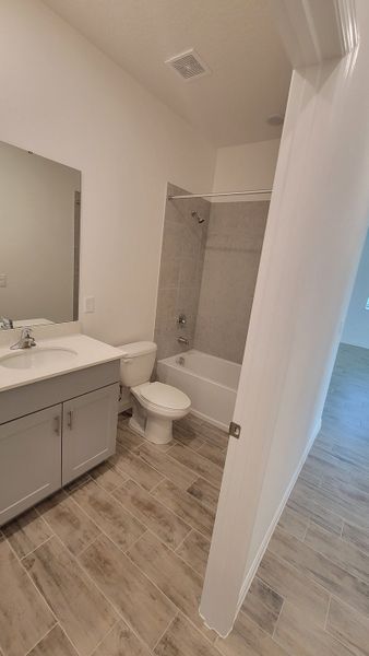 A sleek bathroom with a modern vanity, light tiles, and a built-in bathtub for a stylish look.