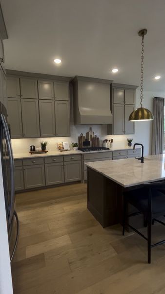 A modern kitchen with sleek gray cabinets, a marble island, and brass pendant lighting. A modern kitchen with sleek gray cabinets, a marble island, and brass pendant lighting.
