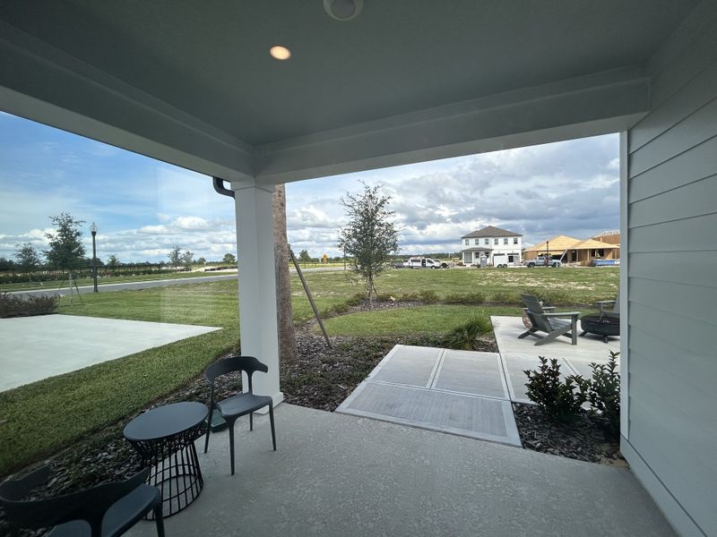 A cozy patio with modern chairs and a table overlooking a developing neighborhood in Trailside by Ashton Woods (Mount Dora, FL).