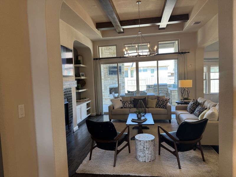 A cozy living room with exposed beams, elegant chandelier, plush seating, and a sleek fireplace for a warm, inviting atmosphere.