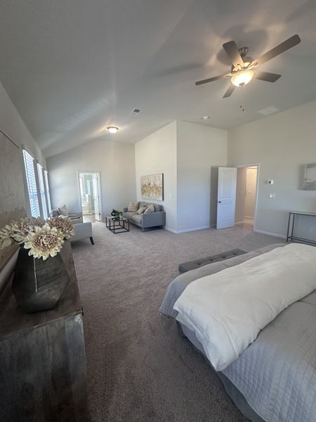 A spacious bedroom with plush carpeting, elegant seating area, and stylish decor, exuding comfort and modernity.