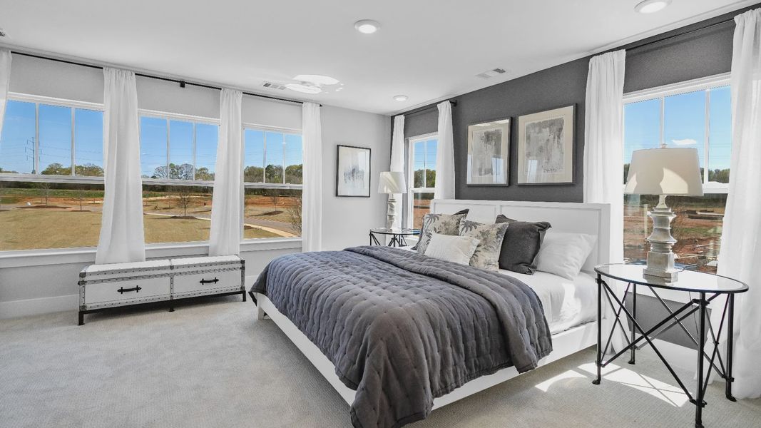 Cozy, inviting primary suite adorned with windows and plush carpet in two story townhome at Hickory Heights by DRB Homes