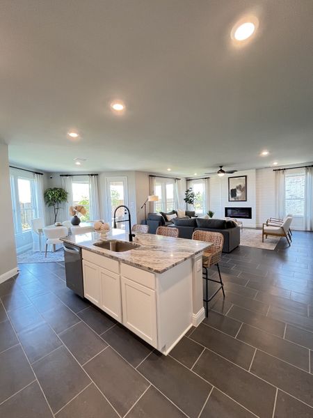 Spacious open-concept living area with sleek tile flooring, a modern kitchen island, and abundant natural light. Spacious open-concept living area with sleek tile flooring, a modern kitchen island, and abundant natural light.