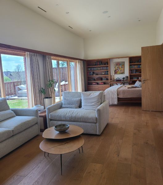 A cozy living room with plush sofas, wooden floors, built-in shelves, and large windows overlooking a serene outdoor space. A cozy living room with plush sofas, wooden floors, built-in shelves, and large windows overlooking a serene outdoor space.