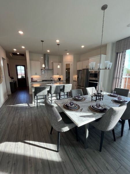 A modern kitchen with elegant marble dining table, cozy gray chairs, and sleek lighting fixtures.