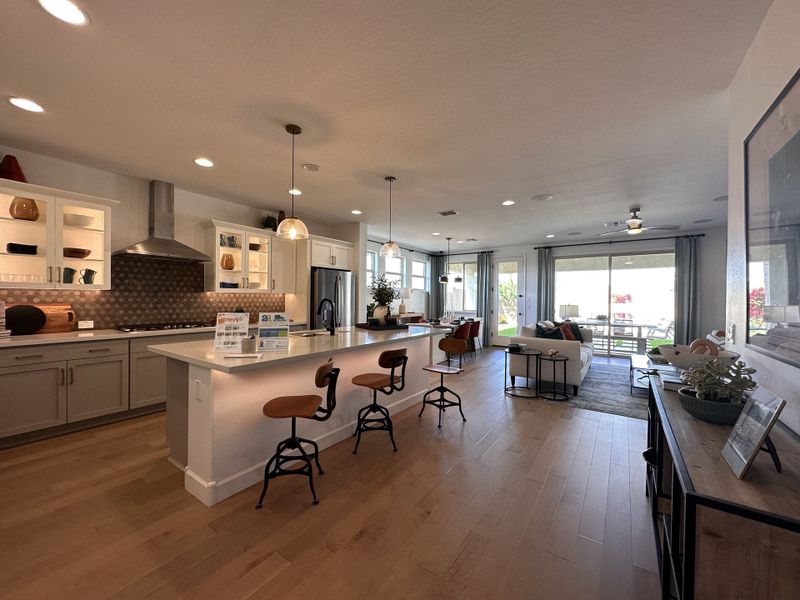 Spacious open-concept kitchen with a modern island, wood floors, and inviting living space leading to outdoor views.