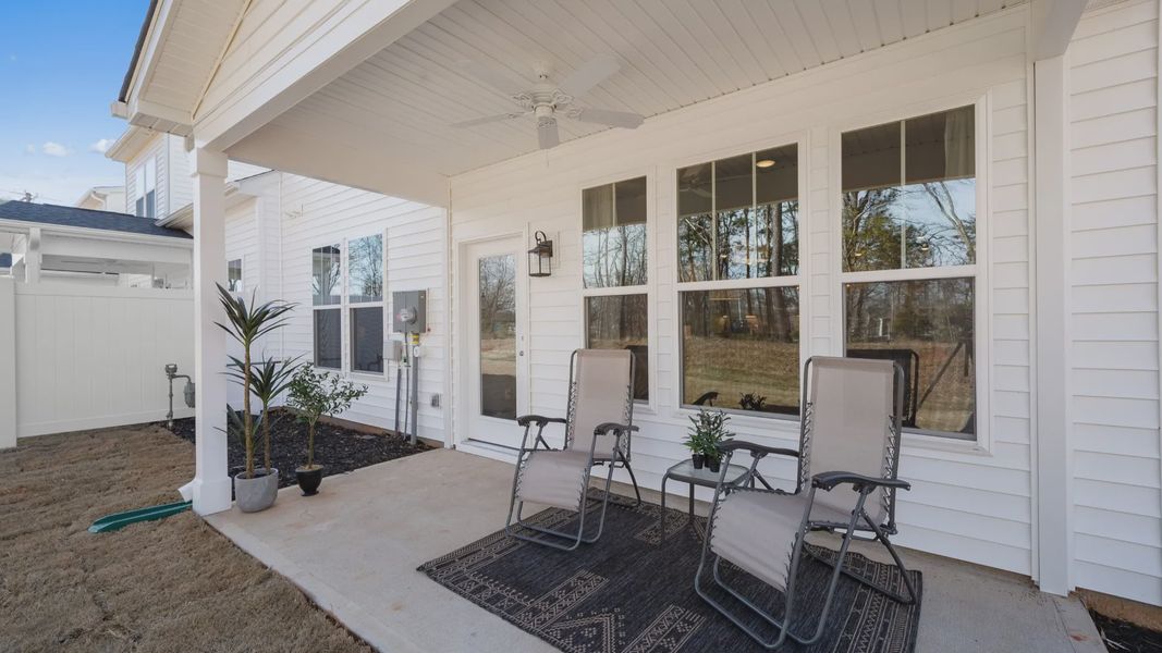 White exterior home with covered back porch with ceiling fan and patio furniture in Anderson, SC at Village at Midway White exterior home with covered back porch with ceiling fan and patio furniture in Anderson, SC at Village at Midway