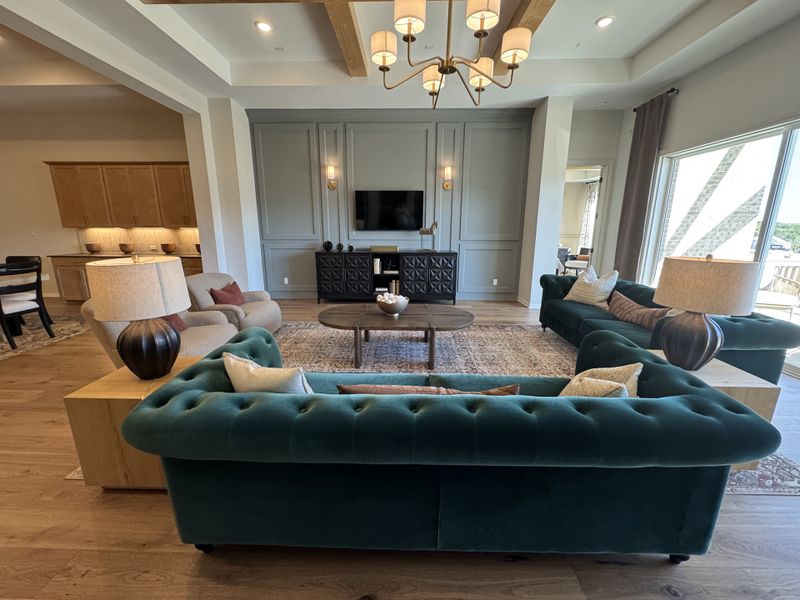 A cozy living room with plush teal sofas, wooden accents, a stylish chandelier, and an elegant built-in TV unit.