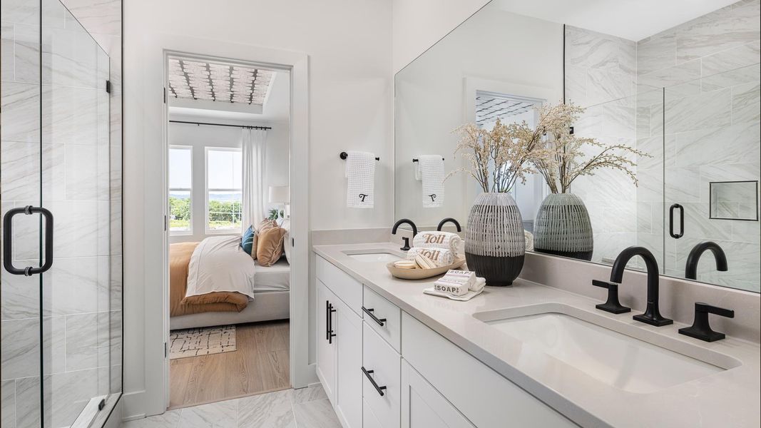 Spa-like primary bath boasts a dual sink vanity and large glass shower