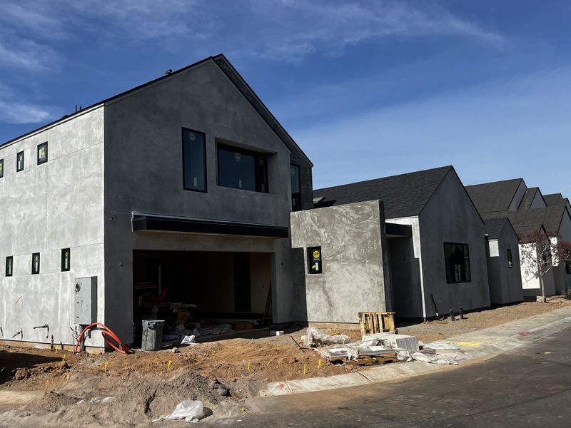 New modern home under construction with a minimalist concrete exterior and large windows.