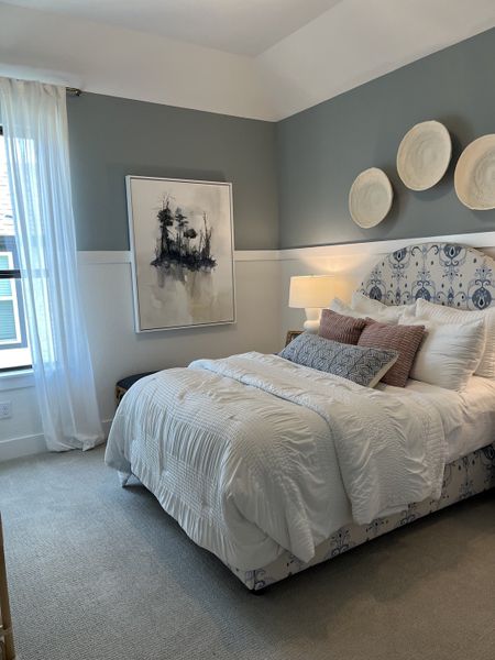 A cozy bedroom featuring a plush bed with patterned headboard, chic wall décor, and soft, ambient lighting.