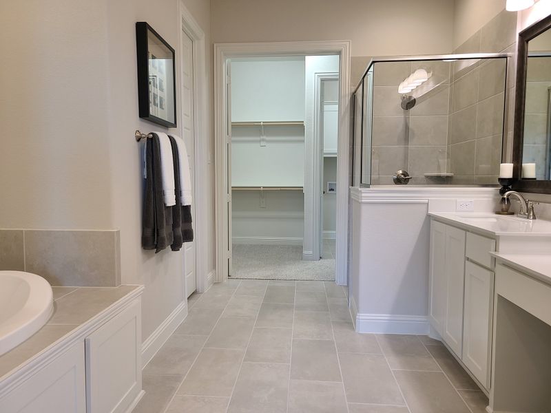 A modern bathroom with a glass-enclosed shower, white cabinetry, and sleek tile flooring.