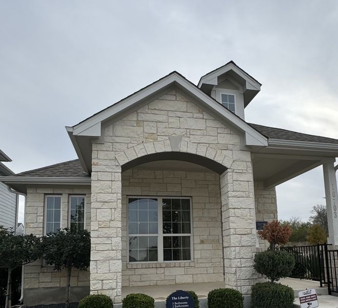 Charming stone façade home with elegant arches in Whisper Valley by Pacesetter Homes (Manor, TX).