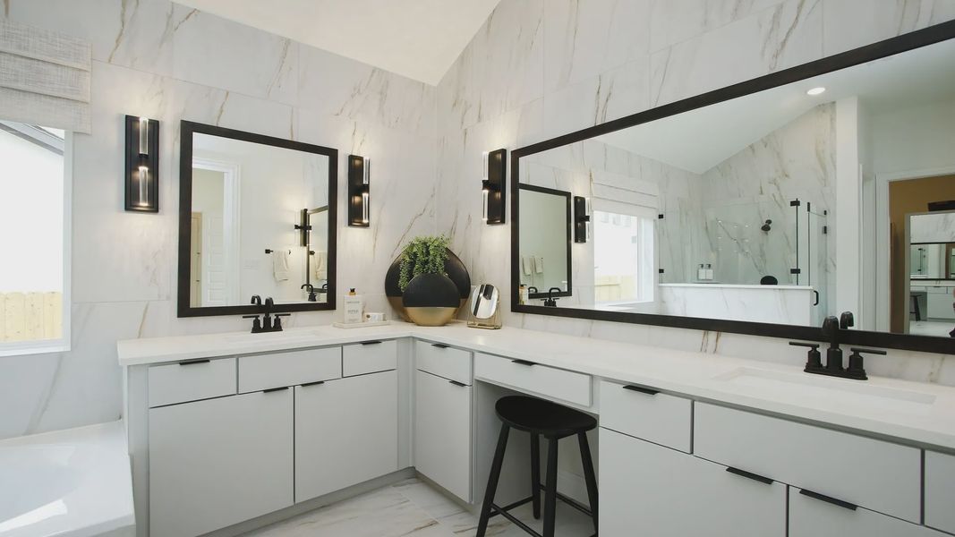 Elegant marble walls and dual vanities with striking black accents enhance this Woodlands Hills bathroom.