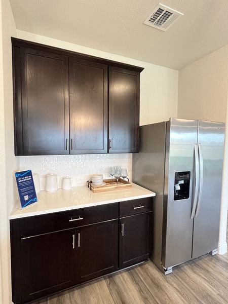 A modern kitchen with dark cabinets, stainless steel fridge, and sleek countertops, featuring elegant backsplash tiles. A modern kitchen with dark cabinets, stainless steel fridge, and sleek countertops, featuring elegant backsplash tiles.