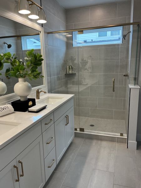 A modern bathroom with a sleek glass shower, double vanity, and elegant lighting.