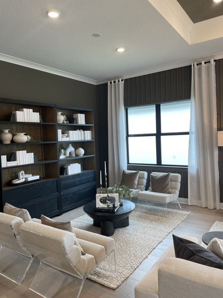 A modern living room with elegant shelving, cozy seating, neutral tones, and soft lighting, creating a sophisticated atmosphere.