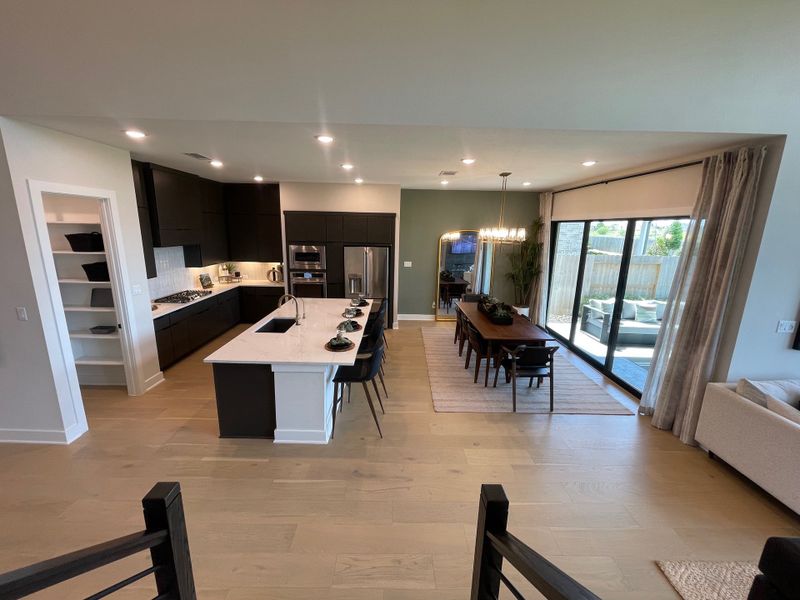 A modern open kitchen and dining area featuring sleek black cabinetry, an island, and large sliding glass doors to the patio. A modern open kitchen and dining area featuring sleek black cabinetry, an island, and large sliding glass doors to the patio.