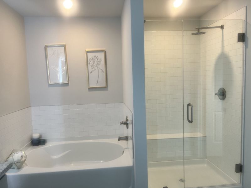 A chic bathroom featuring a soaking tub, glass-enclosed shower, and elegant wall art.