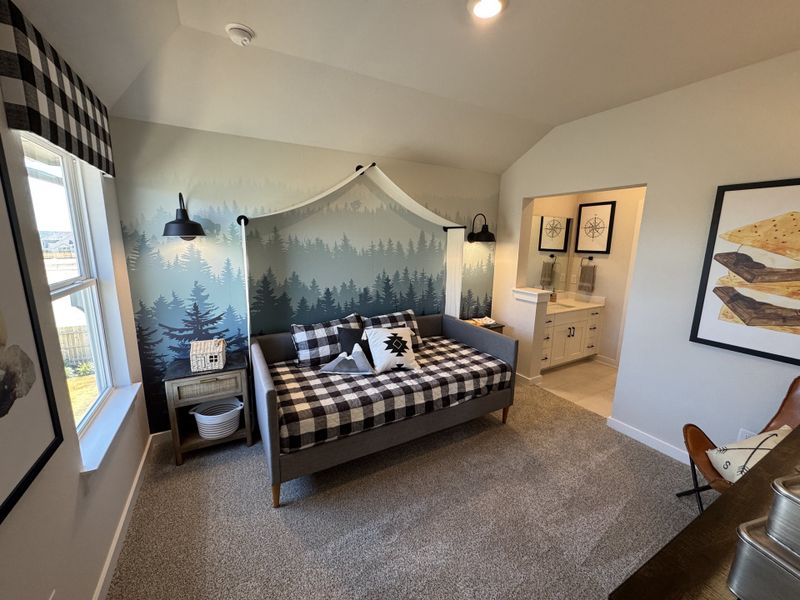 Cozy bedroom with forest-themed mural, checkered bedding, and an adjoining bathroom featuring modern decor.