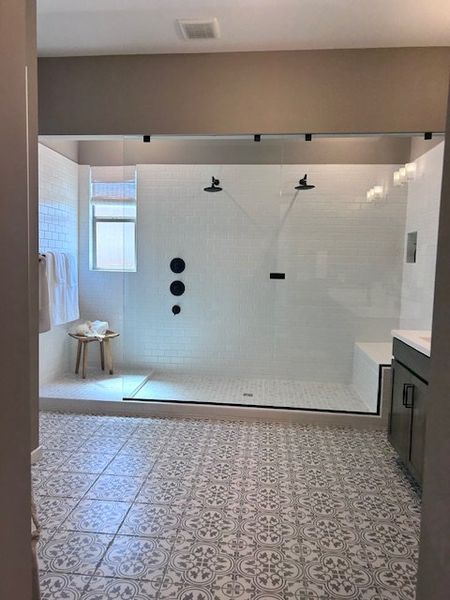 A spacious modern bathroom with a large glass shower, decorative tile flooring, and chic fixtures. A spacious modern bathroom with a large glass shower, decorative tile flooring, and chic fixtures.