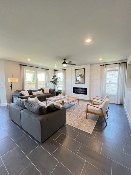A modern living room with sleek tile flooring, cozy gray sectional, and stylish decor surrounding a chic fireplace. A modern living room with sleek tile flooring, cozy gray sectional, and stylish decor surrounding a chic fireplace.