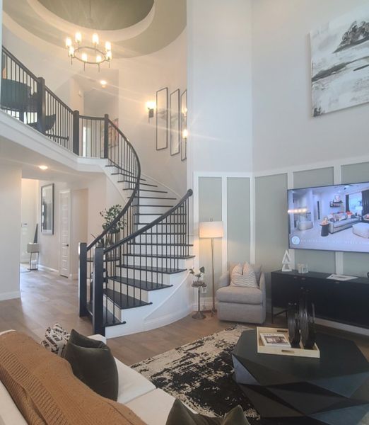 A spacious living room with a grand spiral staircase, modern décor, and elegant lighting.