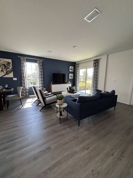 A spacious living room with navy accent walls, sleek flooring, and abundant natural light in Avian Pointe Townhomes by D.R. Horton (Apopka, FL).